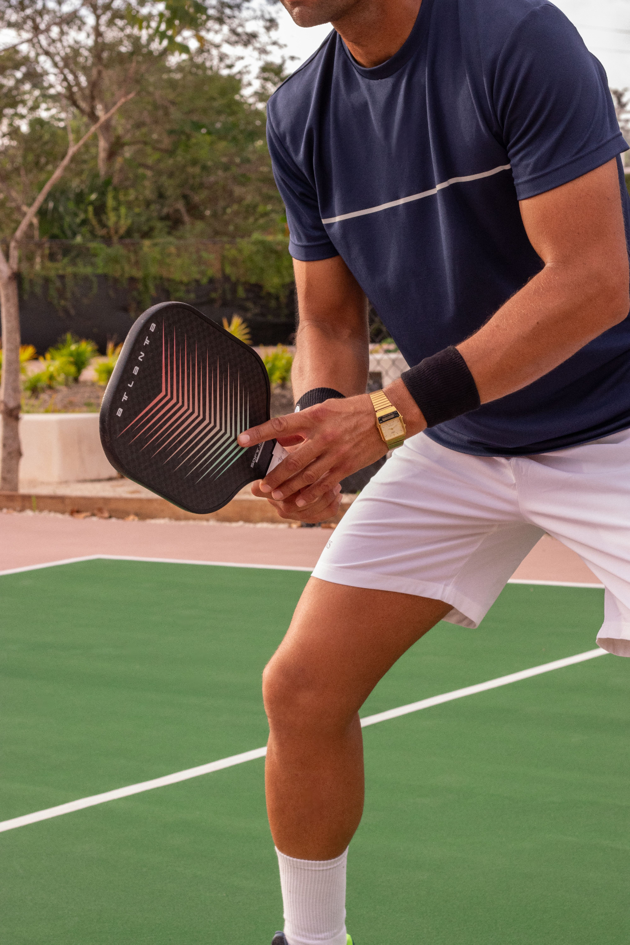 Pickleball player in ready stance holding a paddle on an outdoor court
